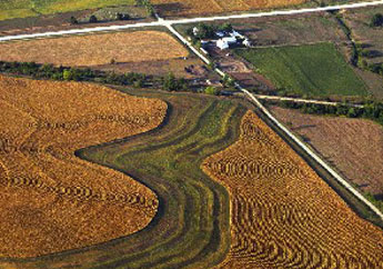 An aerial view of terrace system install on farmland with a farm house sitting at the corner of two roads.